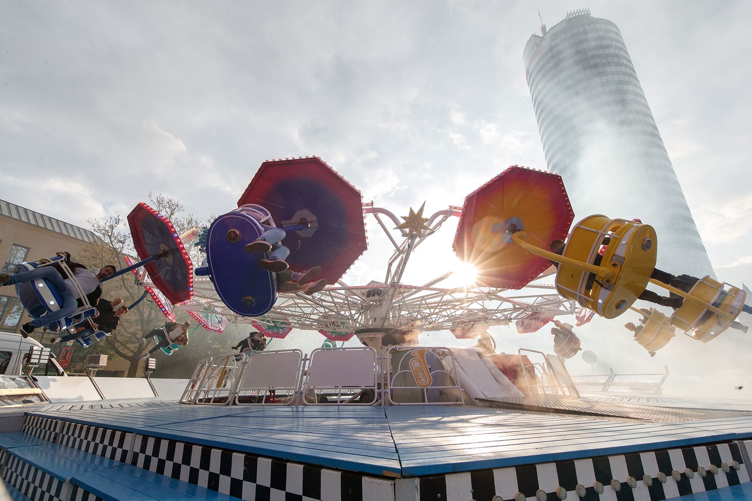 Fahrgeschäft auf dem Jenaer Frühlingsmarkt dreht sich, im Hintergrund sieht man den JenTower