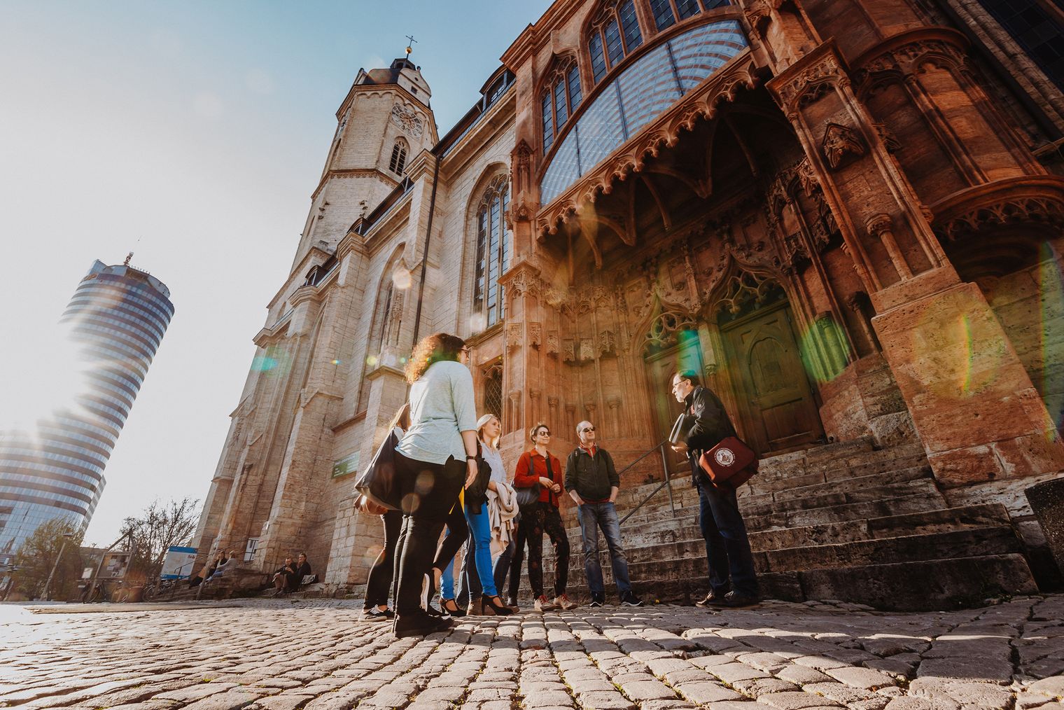 Gruppe einer Stadtführung steht vor der Jenaer Stadtkirche
