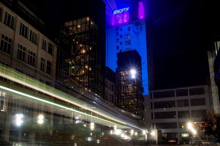 Eine fahrende Straßenbahn hinterlässt Lichtspuren auf dem nächtlichen Campus in Jena